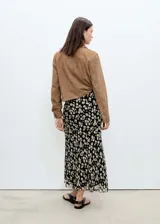 Falda midi negra de gasa con estampado de pequeñas flores blancas.
