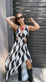 Vestido largo de tela sedosa con estampado de ondas verticales en blanco y negro, escote en V, cut out en la cintura, espalda regulable con lazo y elástico, y tajos laterales.