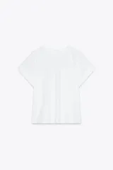 Camiseta blanca de algodón con cuello redondo y manga corta. Presenta un bolsillo de parche en el delantero y detalle de combinación de tejidos a tono.