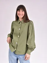 Camisa verde con rayas verticales, cuello clásico, cierre con botones y mangas largas abullonadas.