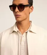 Campera color crema de sarga lisa, con cuello camisero, cierre frontal con cremallera, bolsillos delanteros, puños abotonados y bajo elástico.