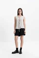 Blusa sin mangas color beige con lazo frontal y textura liviana.