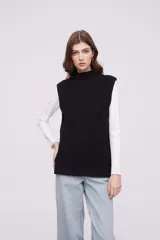 Chaleco negro de punto con cuello alto y sin mangas, con un diseño ajustado.