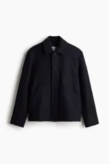 Campera azul marino de lana afieltrada con cuello clásico, cierre frontal con botones, canesú en la espalda, bajo recto y forro interior. Tiene bolsillos de parche en la parte delantera y un bolsillo interior.