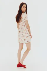 Vestido corto de popelina de algodón color blanco con estampado floral en tonos rosados. Tiene escote cuadrado con elástico, mangas cortas abullonadas con elástico y cuerpo fruncido.