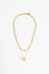Collar dorado de doble cadena, una de eslabones finos y otra de eslabones más grandes, con un dije redondo grabado.