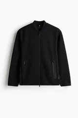 Campera bomber deportiva negra, confeccionada en tejido funcional DryMove™ que absorbe el sudor. Presenta cuello elevado corto, cierre bidireccional, mangas raglán y bolsillos delanteros con cierre y costuras selladas. Posee elástico fino en puños y bajo.