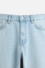 Pantalón de jean celeste de corte slim fit y tapered, con cinco bolsillos, efecto lavado y cierre frontal con cremallera y botón.