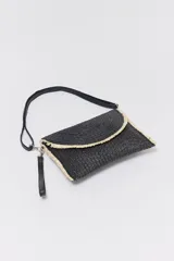 Sobre de rafia trenzada color negro con solapa curva y borde desflecado en color natural. Incluye correa de cuero sintético negra para colgar del hombro o de la muñeca.