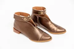 Botín de cuero color borgoña con taco bajo, corte en V en el empeine, pulsera con detalles metálicos y cierre lateral.