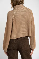 Sweater de punto morado con cierre metálico parcial en el cuello alto y mangas largas.