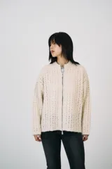 Cárdigan color crema de punto calado, con cuello mao y cierre frontal con cremallera metálica de doble vía.