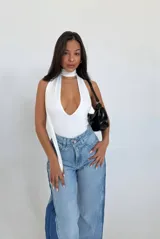 Body blanco con escote halter profundo y tiras finas que se atan al cuello.