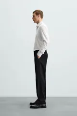 Camisa celeste a rayas verticales blancas, de corte recto, con cuello italiano abierto, mangas largas con puños abotonados y cierre frontal con botones.