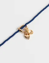 Collar corto de cuentas azul marino con dije de mosquetón dorado en forma de corazón y dijes colgantes de corazón dorado.