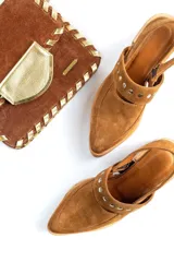 Zapato negro de gamuza con taco de madera y detalle de tachas doradas.