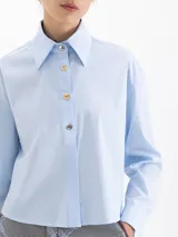 Camisa blanca de manga larga con cuello clásico y botones de diferentes colores.