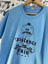 Remera celeste con estampa gráfica de Mr. Meeseeks y calaveras con la frase "Existence is pain".