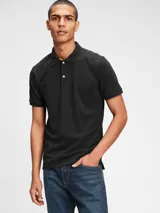 Remera polo de piqué color negro, de corte clásico, con cuello y mangas acanaladas, y tapeta con dos botones blancos.