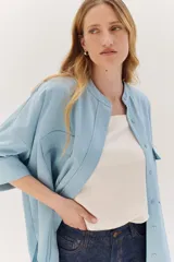 Sobrecamisa celeste de corte recto, con cuello mao, mangas 3/4 con puños y cierre frontal con botones. Tiene dos bolsillos de parche en el pecho.