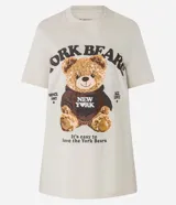 Remera color crema de algodón con cuello redondo y mangas cortas. Presenta un estampado de un oso de peluche con una sudadera que dice "New York" y la inscripción "York Bears".