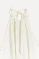 Top blanco de viscosa con cuello halter ajustable con lazadas y espalda descubierta.