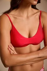 Top de bikini triangular con estampado de hojas rojas y rosadas sobre fondo blanco.