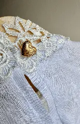 Blusa blanca de lino con cuello Galón estructurado y cierre con botón dorado en forma de corazón en la parte posterior.