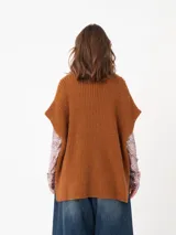 Poncho de tejido grueso color beige, con cuello alto y mangas cortas.