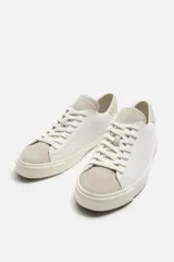 Zapatillas blancas de cuero con detalles en gamuza en la puntera y el talón. Cierre con cordones.