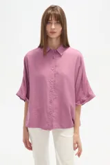 Camisa holgada de viscosa color rosado, con cuello camisero, manga corta y cierre frontal de botones.