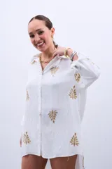 Camisa blanca de manga larga con bordado de hojas doradas.