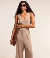 Mono pantalón color beige, de viscosa sostenible, con escote en V cruzado en el frente y en la espalda. Tiene lazo en la cintura.