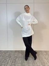 Polerón largo blanco de acrílico con cuello alto y diseño trenzado.