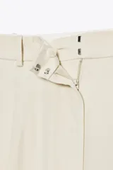 Pantalón negro de tiro alto con trabillas, bolsillos laterales y pinzas. Cierre frontal con cremallera, botón interior y gancho metálico.