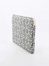 Funda para notebook gris con estampado de hojas en blanco y cierre con cremallera.