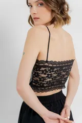 Top crop negro de cuero ecológico con tirantes finos y espalda de encaje floral con base nude.