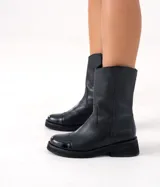 Bota de cuero vacuno color marrón, con caña media, suela de caucho y punta redonda.