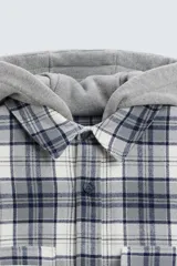 Sobrecamisa de hombre a cuadros azul marino y blanco, corte relaxed fit, con capucha gris de algodón, cuello solapa, manga larga con puños abotonados, bolsillos de parche en el pecho y bolsillos laterales en la cadera.