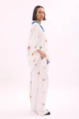 Pantalón blanco de corte amplio con estampado de motivos marinos y cintura elástica con cinturón azul con la inscripción 'Verano Mirando al Mar'.