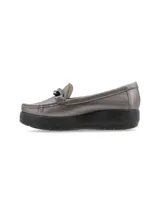 Mocasín de cuero charol negro con plataforma blanca y detalle de hebilla metálica plateada en el empeine.