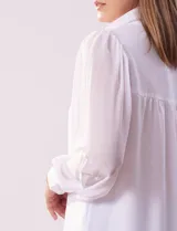 Camisa celeste de gasa, marca Tahari. Cuello con solapa y abertura central con botones ocultos. Manga larga abullonada con puño y botones. Forro de gasa a tono.