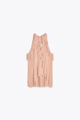Top color rosa viejo de cuello halter ajustable con lazadas. Detalle de abertura en el delantero y volantes en el mismo tejido.