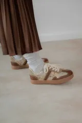 Championes acordonados color beige y dorado con suela marrón.