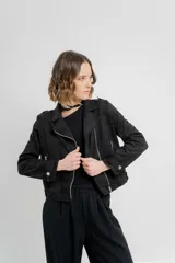 Chaqueta color beige de tela tipo gamuza con elastano, cuello solapa, manga larga con trabillas en hombro, bolsillos delanteros con cremallera metálica y cierre frontal con cremallera.