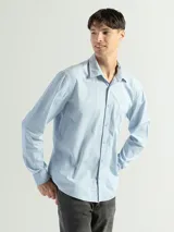 Camisa de manga larga color verde oliva, confeccionada en algodón. Tiene corte clásico, bolsillo en el lado izquierdo del pecho y cierre con botones.