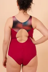 Malla enteriza deportiva color borgoña con espalda nadadora y diseño estampado en la parte superior con degradado de colores y patrón geométrico.