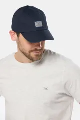 Gorra de béisbol azul marino confeccionada en lona de algodón, con visera curva y parche rectangular con logo en el frente.