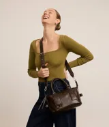 Cartera mini satchel con asa larga ajustable, confeccionada en material sintético PU, con cierre de cremallera y efecto desteñido.