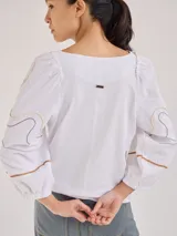 Remera gris de algodón con mangas color beige con bordados de líneas en blanco, amarillo y gris.